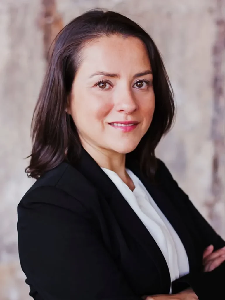 Professional portrait of a woman with dark hair wearing a black blazer and white blouse.