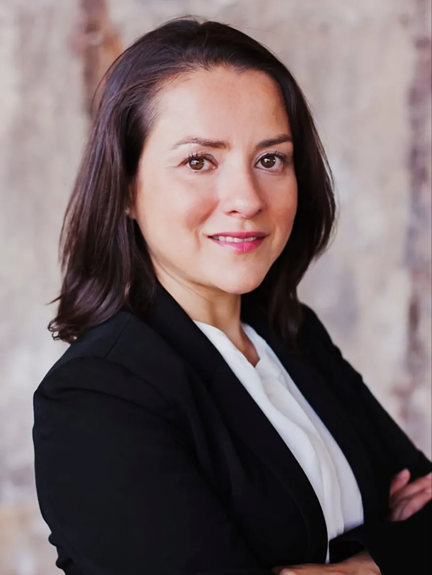 Professional portrait of a woman with dark hair wearing a black blazer and white blouse.