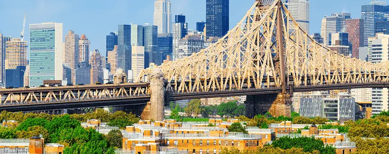 Panoramic view of a large steel bridge with Manhattan skyscrapers in the background.