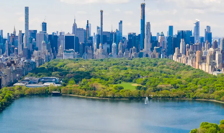 Aerial view of Central Park with lush green trees and surrounding New York City skyscrapers.