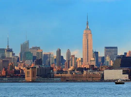 Panoramic view of New York City skyline featuring the Empire State Building under a clear blue sky.