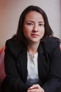 Portrait of a professional woman with dark hair wearing a black blazer and white blouse.