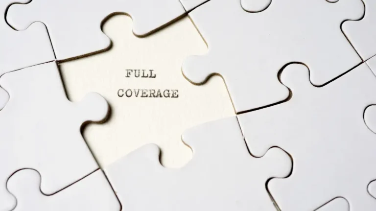 Close-up of white puzzle pieces with one piece missing, revealing the text "FULL COVERAGE" underneath.