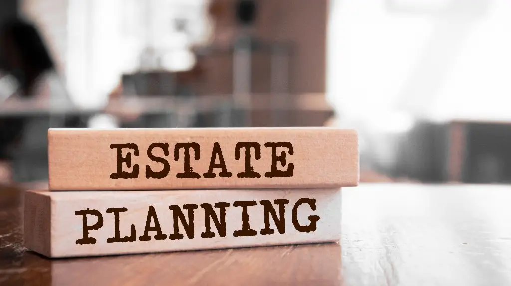 Two wooden blocks stacked on a table with the words "ESTATE PLANNING" printed in bold brown letters.